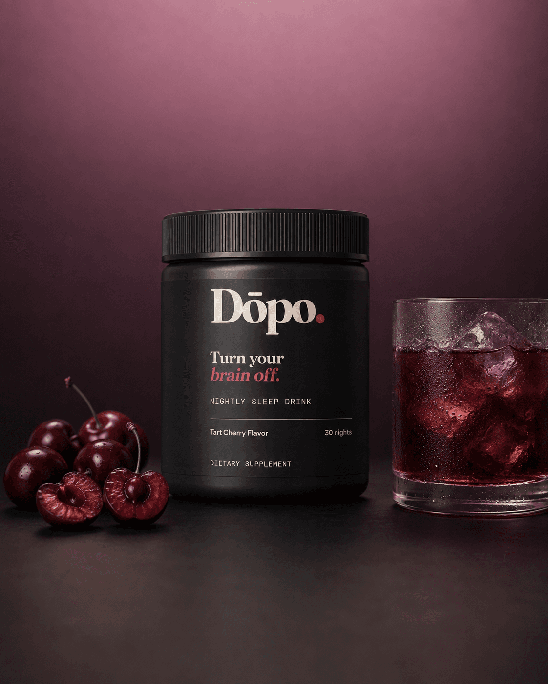 Dōpo Tart Cherry tub beside a glass of ruby drink and fresh cherries on a deep plum studio surface