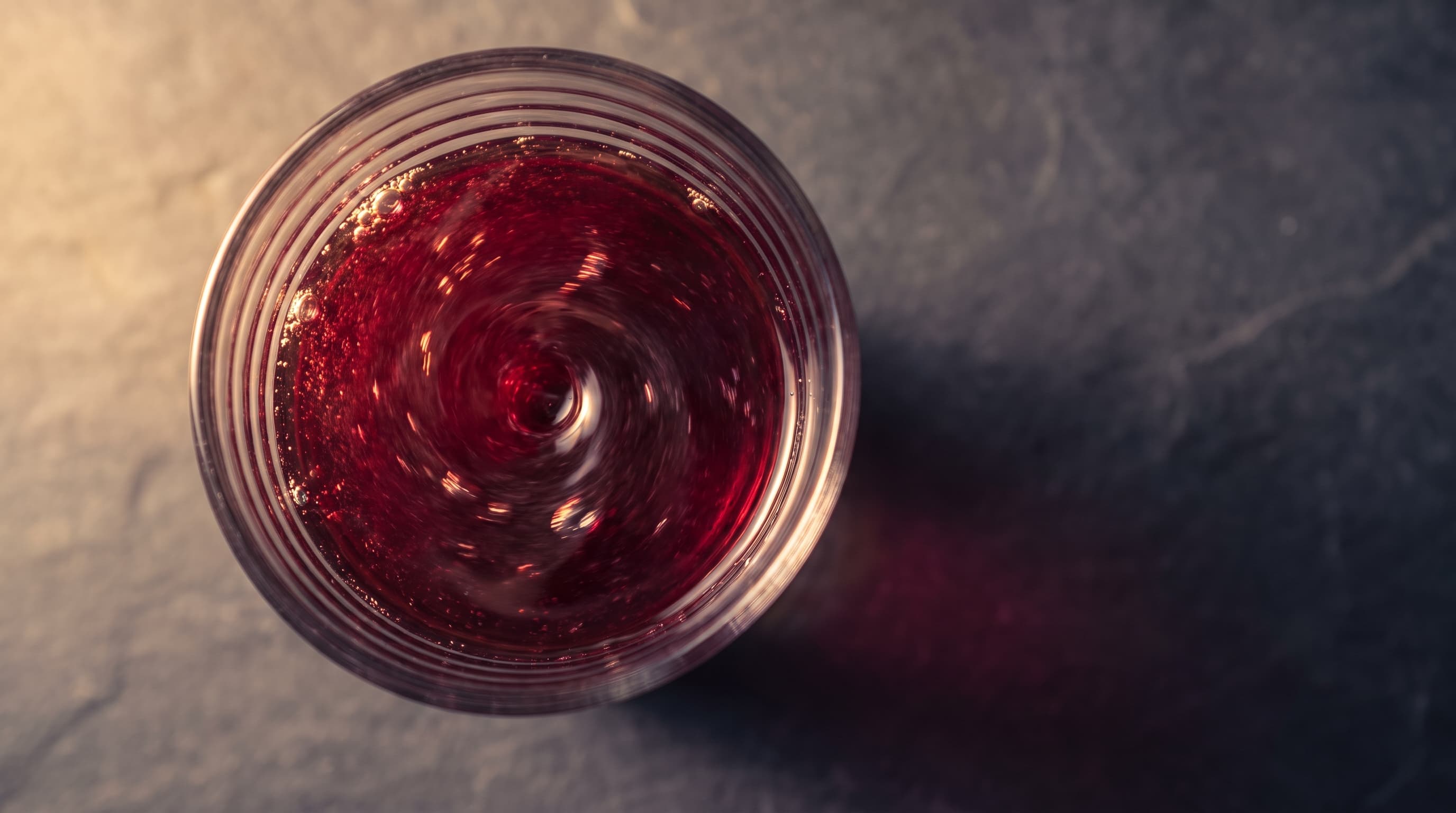 Overhead view of tart cherry liquid swirling in a ribbed glass.